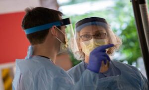 Two healthcare workers with face shields, masks and other PPE during the COVID-19 outbreak.