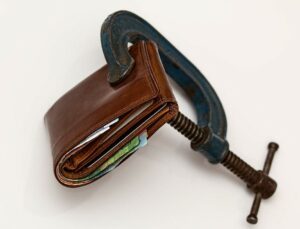 A wallet being squeezed by a C-Clamp.