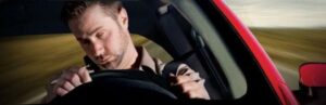 A drowsy driver falling asleep at the wheel when speeding down the road.