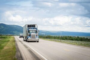 semi truck on road with mountains in background