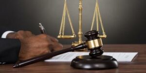 A lawyer working and writing for a wrongful death claim, with a court gavel and the scale of justice in the background.